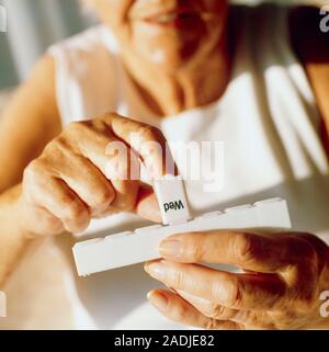 Pill box. Elderly woman taking medication from a pill box. The pill box contains daily doses of pills for up to seven days. This reminds the patient t Stock Photo