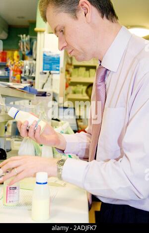 This is a real situation. Image not to be used in a defamatory context. MODEL RELEASED. Pharmacist checking the labels on bottles of medicine. Stock Photo
