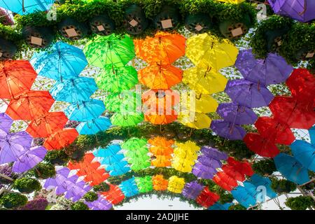 Arch made of colorful umbrellas on blue sky. Multi colored umbrellas background. Stock Photo