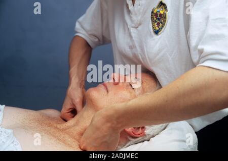 Osteopathic neck treatment. Osteopath stretching the soft tissue in an elderly female patient's neck. Other types of treatment involve manipulation or Stock Photo