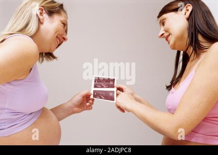 Two pregnant women looking at ultrasound scans. Images of a foetus can be produced using ultrasound. High frequency sounds are passed through the abdo Stock Photo