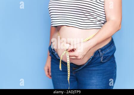 Overweight, obese woman in sports bra and leggings holding her