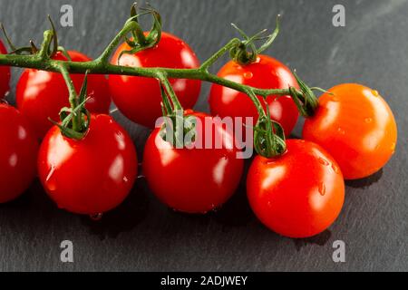 Drops of water falling on the black slate from tomato branch Stock Photo