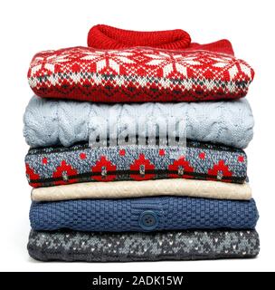 Stack of folded various knitted sweaters and pullovers in a clothes store or at a wardrobe on white background Stock Photo