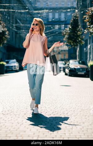 Happy woman gesturing while talking on the phone Stock Photo