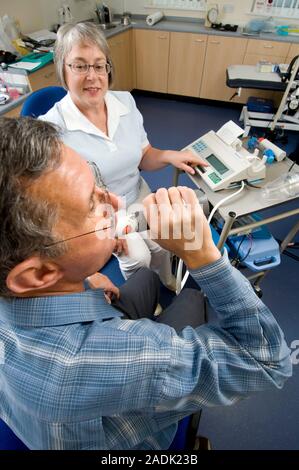 MODEL RELEASED. Lung function test. Patient breathing into a spirometer during a lung function test. The spirometer measures the amount and speed of a Stock Photo