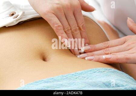 MODEL RELEASED. Abdominal examination. General practitioner palpating a female patient's abdomen. Stock Photo