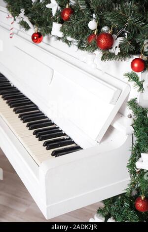 Keys on white upright piano with christmas decor with red balls Stock Photo