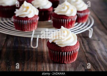 Red velvet cupcakes on a cooling rack on a rustic wooden table Stock Photo