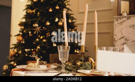 Table with candles served for Christmas dinner in living room, close up view Stock Photo