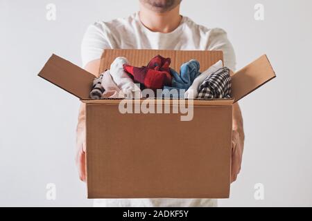 Unrecognizable man holding a cardboard box full of clothes close-up. Stock Photo