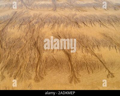 Patterns in golden beach sand caused by flowing water Stock Photo