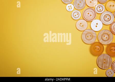 Buttons of pastel colors pink, beige, white, pearl on a yellow background. Stock Photo