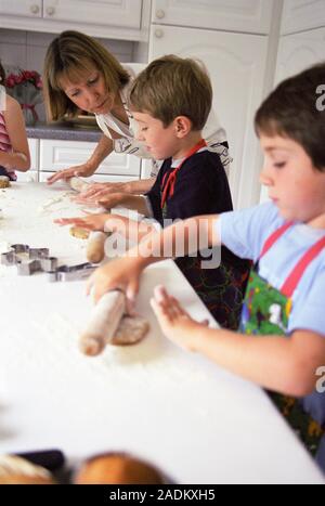 Making biscuits. 5-year-old boys being watched by an adult while they roll out biscuit dough. Biscuits will be cut out of the dough using shaped cutte Stock Photo