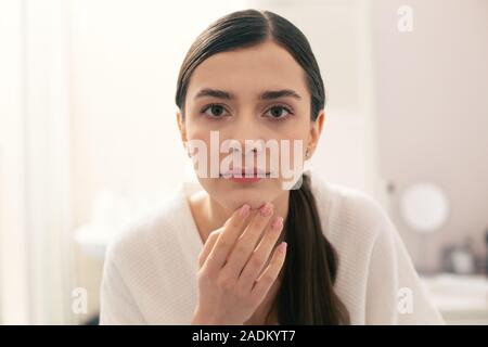 Long haired woman touching her chin and looking interested Stock Photo