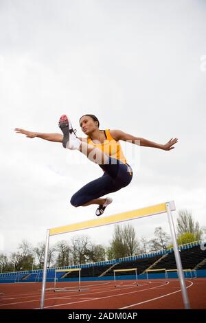 MODEL RELEASED. Athlete clearing a hurdle. Stock Photo