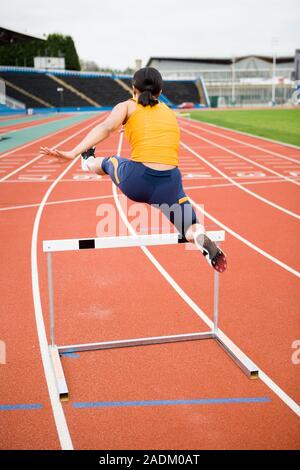 MODEL RELEASED. Athlete clearing a hurdle. Stock Photo