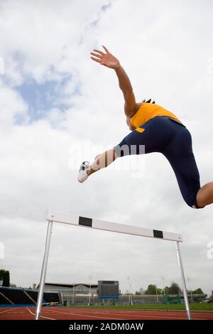 MODEL RELEASED. Athlete clearing a hurdle. Stock Photo