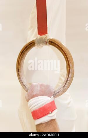 MODEL RELEASED. Gymnast gripping a ring. This piece of gymnastic apparatus is used only by male gymnasts. The gymnast's hands and sometimes the rings Stock Photo