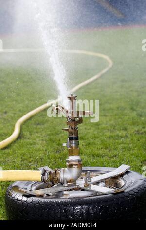 Water sprinkler watering the grass at a sports arena. Stock Photo