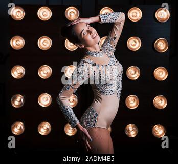 On the backstage. Beautiful female assistant of magician posing in the studio with lights behind her Stock Photo