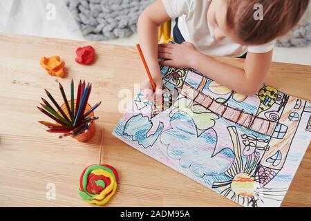 Conception of art. Cute little girl in art school draws her first paintings by pencils and markers Stock Photo