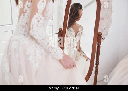 Reflection of bride in the mirror. The process of fitting the dress in the studio of hand crafted clothes Stock Photo