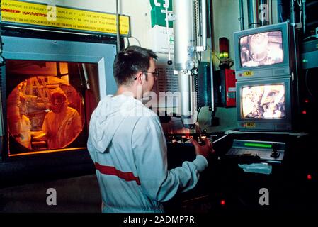 Nuclear safety research. Nuclear power station worker operating remote handling equipment during a simulation of a core meltdown. Another worker, in s Stock Photo