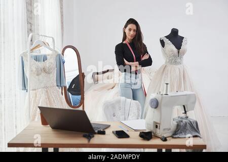 Nice day in clean room with proud owner. Female fashion designer works on the new clothes in the workshop Stock Photo