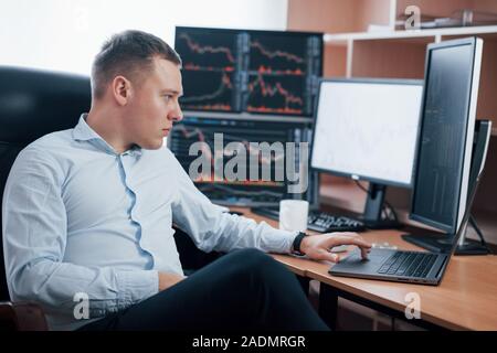 Too many things needed to be successful. Man working online in the office with multiple computer screens in index charts Stock Photo