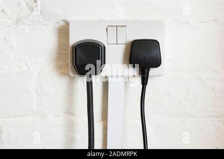 Electrical power socket switched on with two plugs. This BS 1363 (British Standard) three-pin plug socket is used to connect electrical devices to the Stock Photo