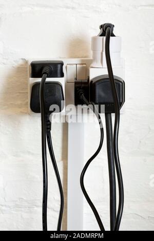 Overloaded electrical power socket. Power sockets containing a plug adaptor and block extension sockets overloaded with plugs. Power sockets are used Stock Photo