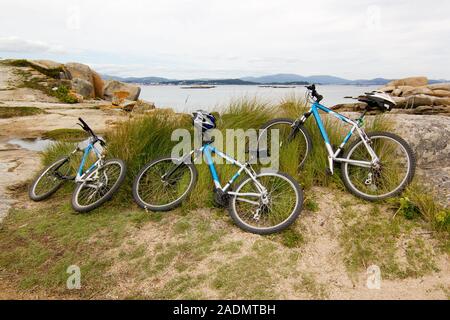 Three bike lying on the beach with atlantic ocean coastline at background. Family leisure concept. Illa de Arousa, pontevedra, Spain Stock Photo