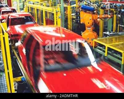 Robotic production line. Time-exposure image of car bodies that have been produced on a robotic production line. A robot arm (orange) is at upper righ Stock Photo
