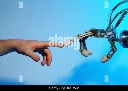 Robotic imitation. Robotic hand imitating the position of a human hand. This robotic hand has been built by Graaltech, a company founded by researcher Stock Photo