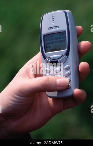 Mobile phone texting. Thumb being used to type a text message on a mobile phone. Repeated use of the thumb to type messages has led to a rise in RSIs Stock Photo