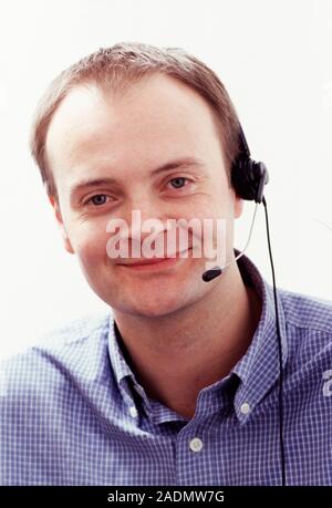 Telephone headset. Smiling man wearing a hands-free telephone headset. Stock Photo