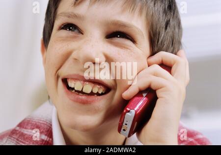 MODEL RELEASED. Mobile phone use. Eight-year-old boy talking on a mobile phone. Stock Photo