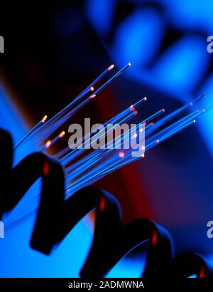 Optical fibres. A bundle of optical fibres and a telephone handset and handset cable. The end of the optical fibres are bright indicating that light i Stock Photo