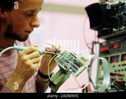 Circuit board manufacture. Electrical engineer soldering a printed circuit board at a factory. Photographed in Germany. Stock Photo