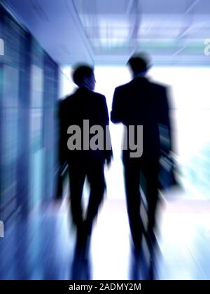 Businessmen having a discussion while walking down a corridor. Stock Photo