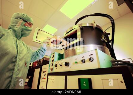MODEL RELEASED. MEMS production. Clean room technician using a thin film deposition machine to produce MEMS (microelectromechanical systems) devices. Stock Photo