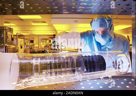 MODEL RELEASED. MEMS production. Clean room technician lifting a container of silicon wafers being used to produce MEMS (microelectromechanical system Stock Photo