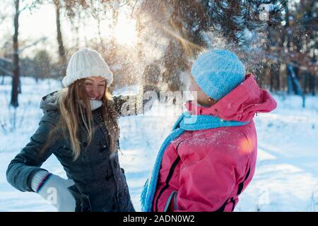 Winter fun activities. Mother and adult daughter shaking branches with snow outdoors. Family relaxing for holidays Stock Photo