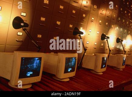 Computers. Conceptual image of computer monitors in front of a bank of filing cabinets. This could represent the huge storage capacity of computers du Stock Photo