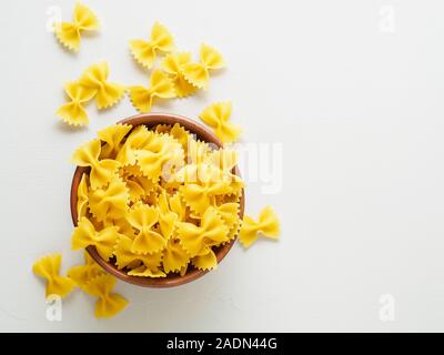 Pasta farfalle in wooden bowl on gray stone table. Top view, empty place for text. Stock Photo