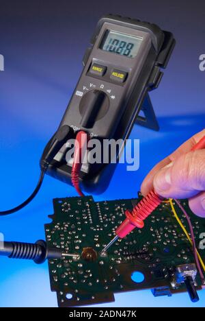 Digital multimeter. Technician using a multimeter to test the electrical resistance across two points on a circuit board. Electrical resistance, measu Stock Photo