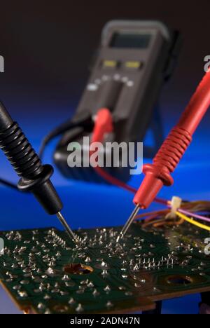 Digital multimeter being used to test the electrical resistance across two points on a circuit board. Electrical resistance, measured in ohms, is a me Stock Photo
