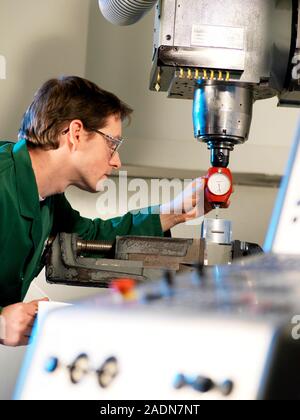 Metalwork. Metalworker using a 3D taster (red) to align the cutter of a CNC (computer numerical control) milling machine before use. The machine consi Stock Photo