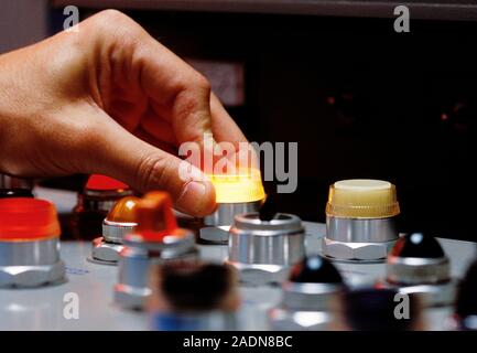 Control panel. Hand pressing a lit button on an industrial control panel. Stock Photo